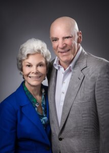 A photo of Robert and Janice McNair posing in front of a grey background.